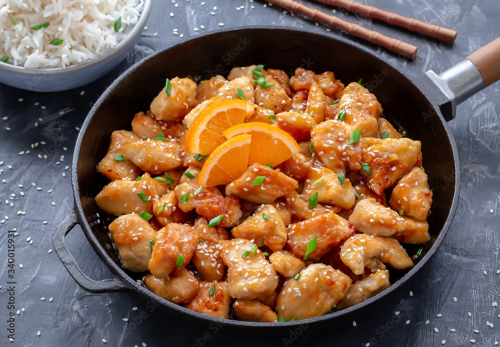 Asian Orange Chicken served in frying pan with fluffy white rice Asian Orange Chicken served in frying pan with fluffy white rice