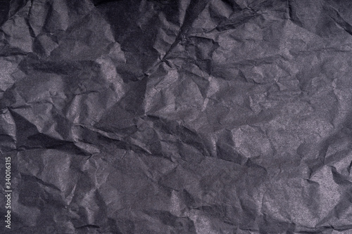 Dark wrinkled creased black paper poster texture. Blank crumpled grainy paper textured surface. Smudged grungy cardboard with fiber. Close up. Material tissue for packing