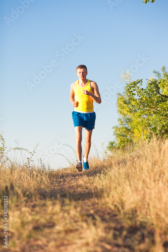 Young man running on a rural road during sunset