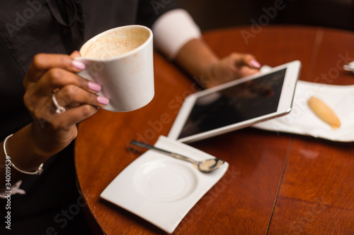 Black african american young yoman drinking coffee and using a tablet
