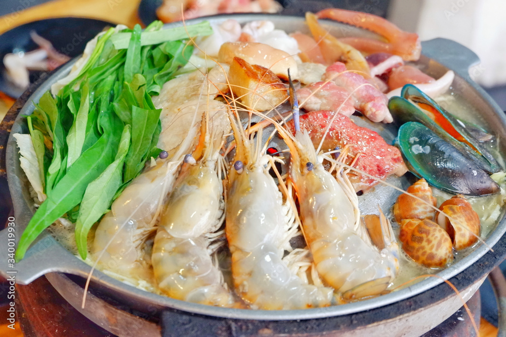 Sliced Pork and seafood on Thai Styled Coal Grill and Shabu Pan.Shrimp Clams in a Hot Pan.Close up.
