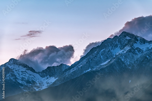 High mountains with snowy peaks at sunset in clouds and fog © Dmitrii Potashkin