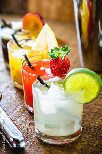 Glasses of alcoholic drinks with fruits, drink known as mojito or Caipirinha. Lemon, passion fruit, strawberry watermelon and plum flavors. photo