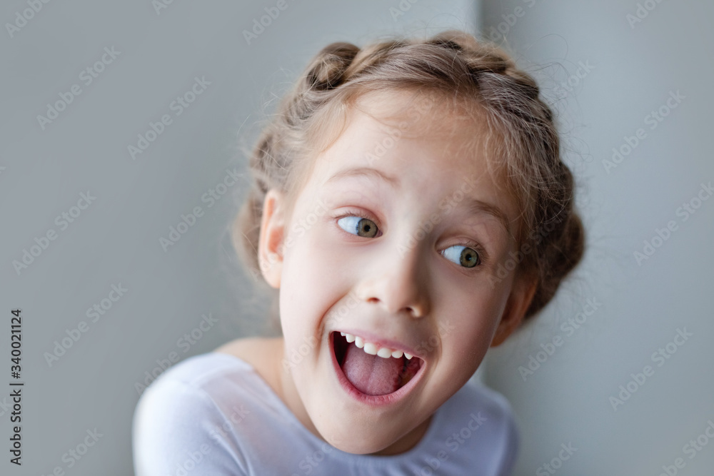 Large portrait of a little girl. Looking at the camera, she is genuinely, happily giggles-smiles. On a gray background. Large portrait of a little girl. Looking at the camera, she is genuinely, happily giggles-smiles. On a gray background.