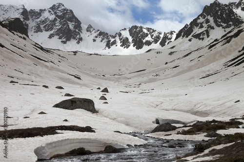 River with snow bridges in high snowy mountains at spring evening