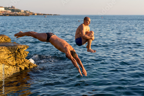 Two guys diving from a cliff