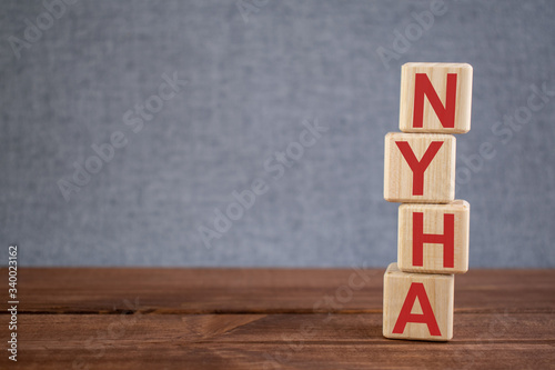 Abbreviation NYHA (New York Heart Association) text acronym on wooden cubes on dark wooden backround. Medicine concept. photo
