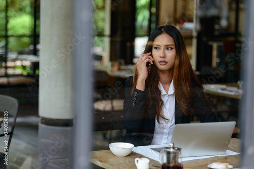 Young Asian businesswoman talking on the phone at the coffee shop