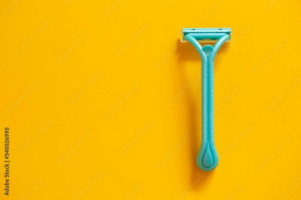 Blue razor on a yellow background top view. The concept of hygiene, beauty, shaving. Blue razor on a yellow background top view. The concept of hygiene, beauty, shaving.