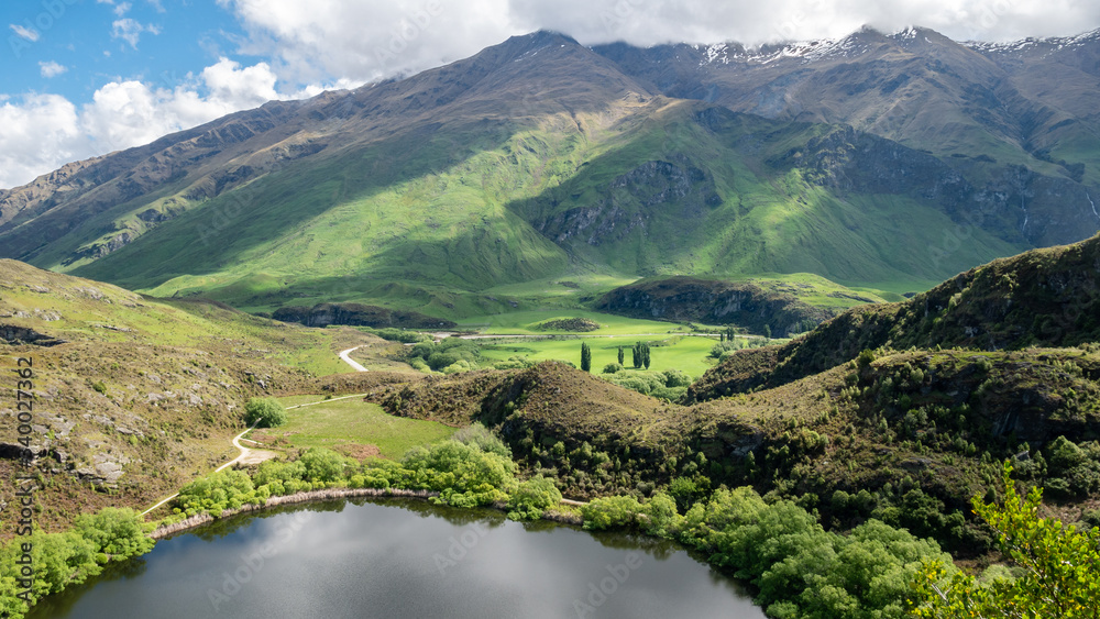 Small lake with lush green hills, landscape shot made in New Zealand