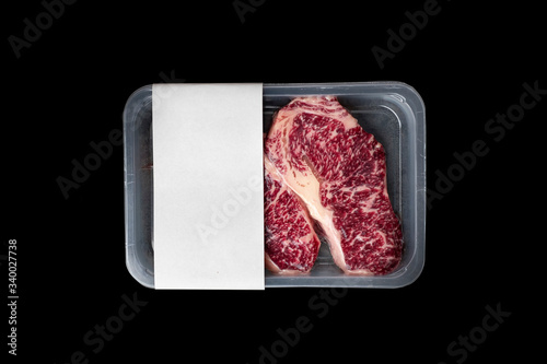 Raw Striploin marbled beef steak vacuum Packed isolated on black, logo mockup