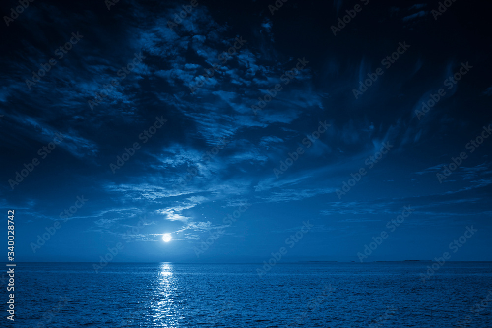 This photo illustration of a deep blue moonlit ocean and sky at night  would make a great travel background for any travel or vacation purpose. - obrazy, fototapety, plakaty 