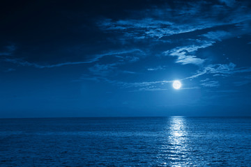 This photo illustration of a deep blue moonlit ocean and sky at night  would make a great travel background for any travel or vacation purpose.