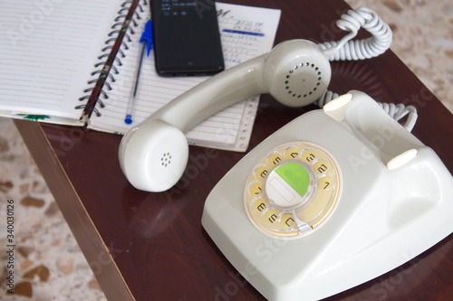 old phone next to contact book and mobile phone on table