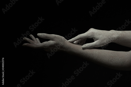 Hands of a living sculpture of a young woman, one hand resting on the other