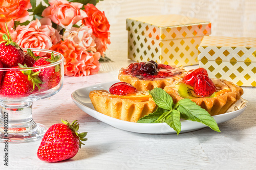 Festive still life with cakes, strawberries, gift boxes
