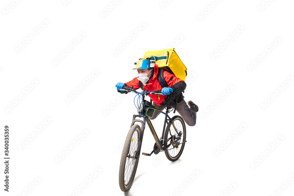 Fototapeta premium Too much orders. Contacless delivery service during quarantine. Man delivers food during isolation, wearing gloves and face mask. Taking pizza on bike isolated on white background. Safety. Hurrying up