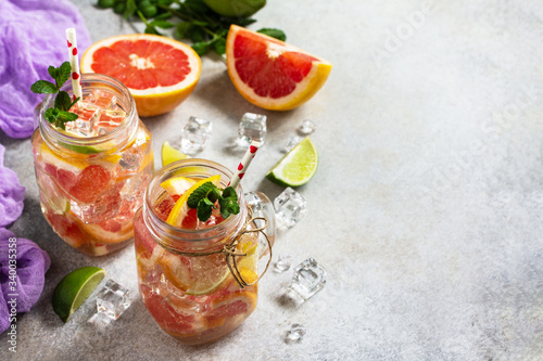 Summer ice refreshing drink. Fresh mojito cocktail with grapefruit, lime and mint in a glass on a gray stone background. Copy space.