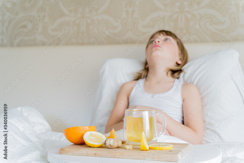 Little sick girl in bed with cup of antipyretic drugs for colds,flu.Tea with citrus vitamin C,ginger root,lemon,orange.Wooden tray. Home self-treatment.Medical quarantine covid-19 coronavirus therapy Little sick girl in bed with cup of antipyretic drugs for colds,flu.Tea with citrus vitamin C,ginger root,lemon,orange.Wooden tray. Home self-treatment.Medical quarantine covid-19 coronavirus therapy