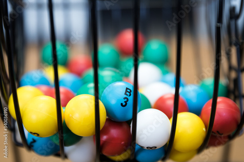 A close up of a bingo cage filled with multi-colored balls. Each ball has a letter and number on it that corresponds to a number on the player's bingo card. Bingo is a game of chance.