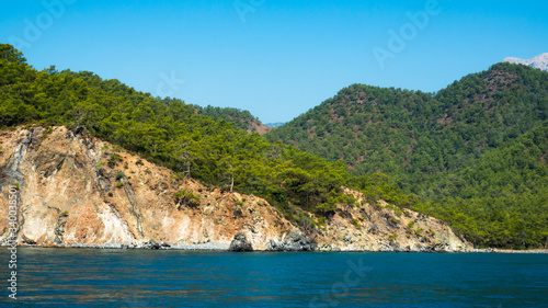 Beautiful deep sea with small waves and steep cliffs on the shores of the Mediterranean Sea with trees and caves. © kinomaster