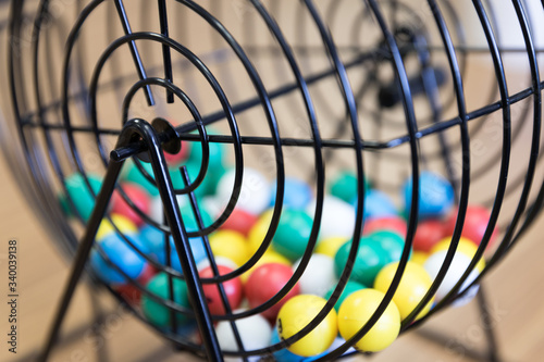 A close up of a bingo cage filled with multi-colored balls. Each ball has a letter and number on it that corresponds to a number on the player's bingo card. Bingo is a game of chance.