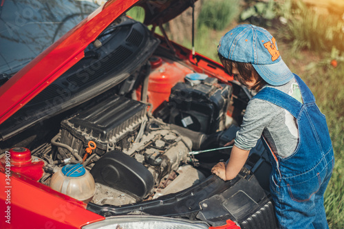Little child trying to fix broken real car. Dreaming to be auto technician © serhiilysenko
