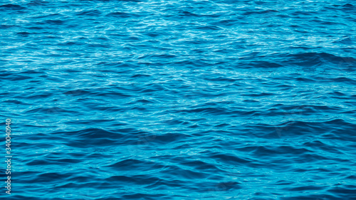 Ripples in the empty blue sea cause sparkles when light shine to surface at sunny day. Close up.