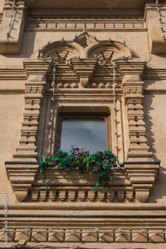 Beautiful vintage window on an old building with fresh flowers on a windowsill.