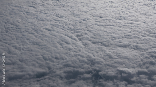 The view from the window of an airplane flying above the thick white clouds. Skyscape