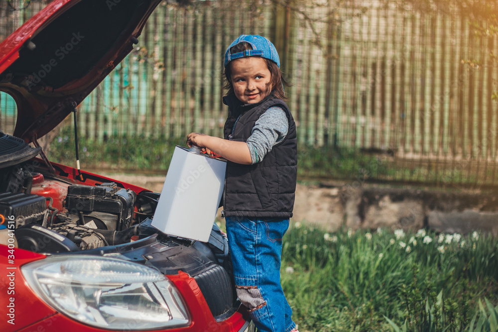 Little pretty child with a can of oil near the hood of a car. She is trying to fix broken car.
