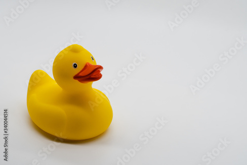 A studio shoot of a rubber duck on a neutral white background. The duck is in one side of the image.