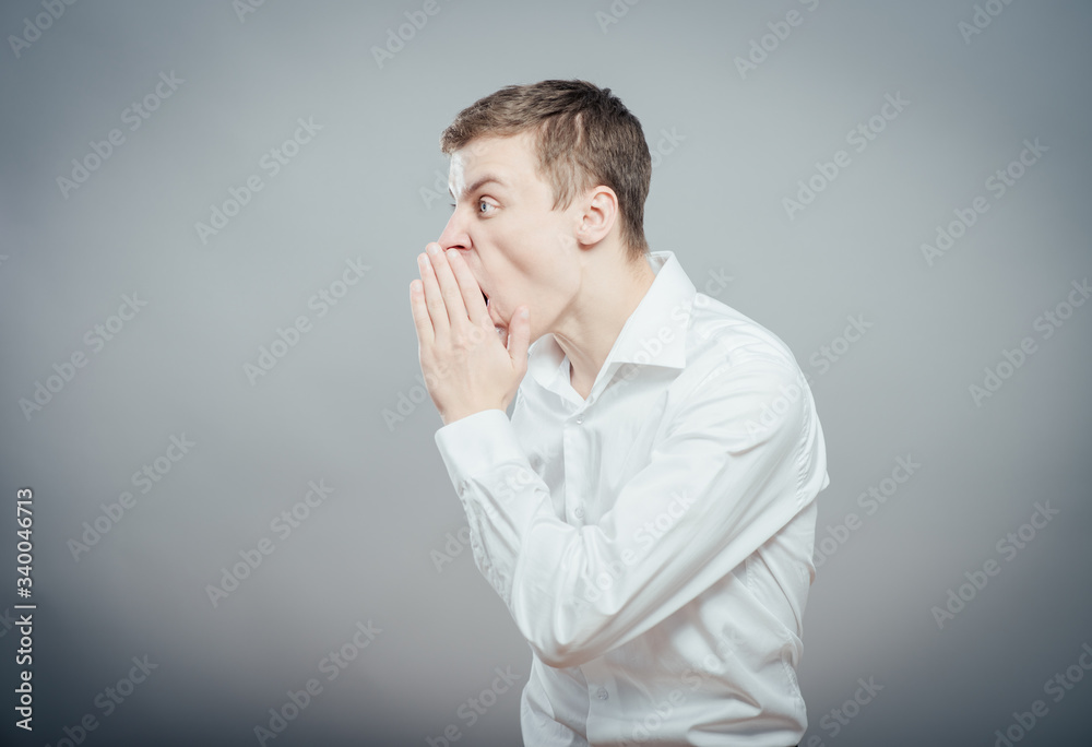 Young man shouting with hand cupped to his mouth Young man shouting with hand cupped to his mouth