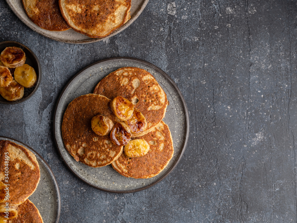 Oatmeal banana pancakes with honey and babana slices on ceramic plate. Healthy easy making morning breakfast. Homemade sugar free and gluten free food. Concrete background, top view. Copy space.