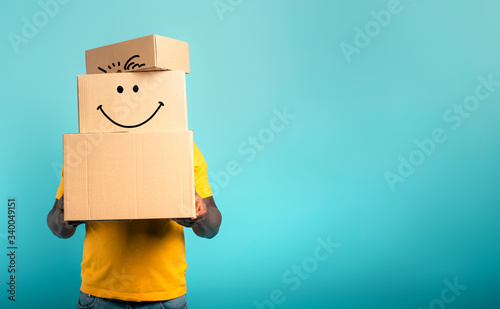 Man is hidden by too many received packages. Cyan background photo