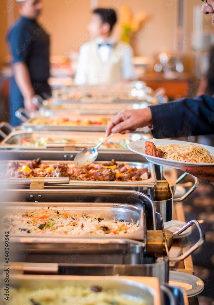 A person serving his meal to a white plate from a buffet in a hotel