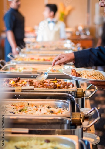 A person serving his meal to a white plate from a buffet in a hotel