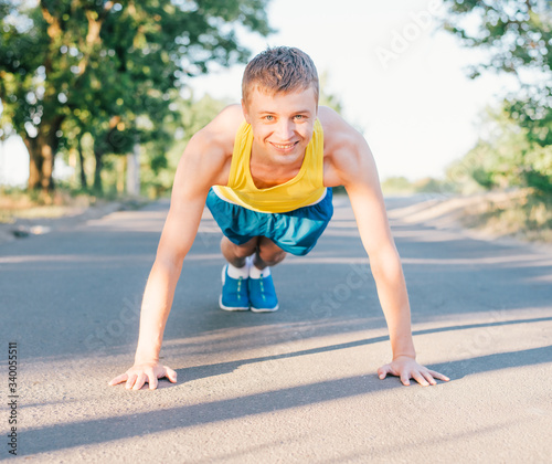 Closeup portrait, young healthy handsome man performing pushup outside on road in park