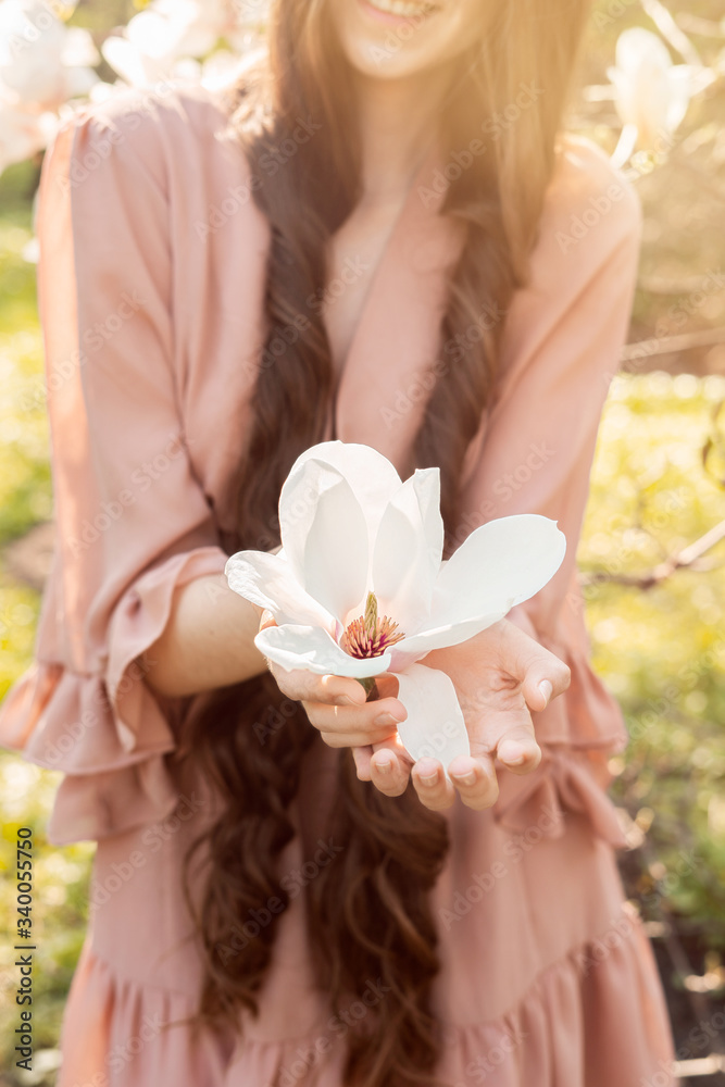 Naklejka premium Closeup of women hand with holding in the palms a blossoming magnolia. Environmental protection concept. Springtime.