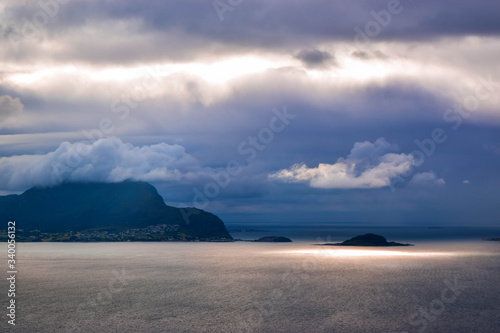 Purple sunset over the island Godoy (Godoya), which is located near the city of Alesund. Rays of the sun illuminate the Atlantic Ocea, passing between low clouds. Dramatic cloudy landscape. Norway. photo