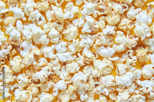 Caramel popcorn isolated on a yellow background, scattered. Mockup, frame of popcorn, top view.