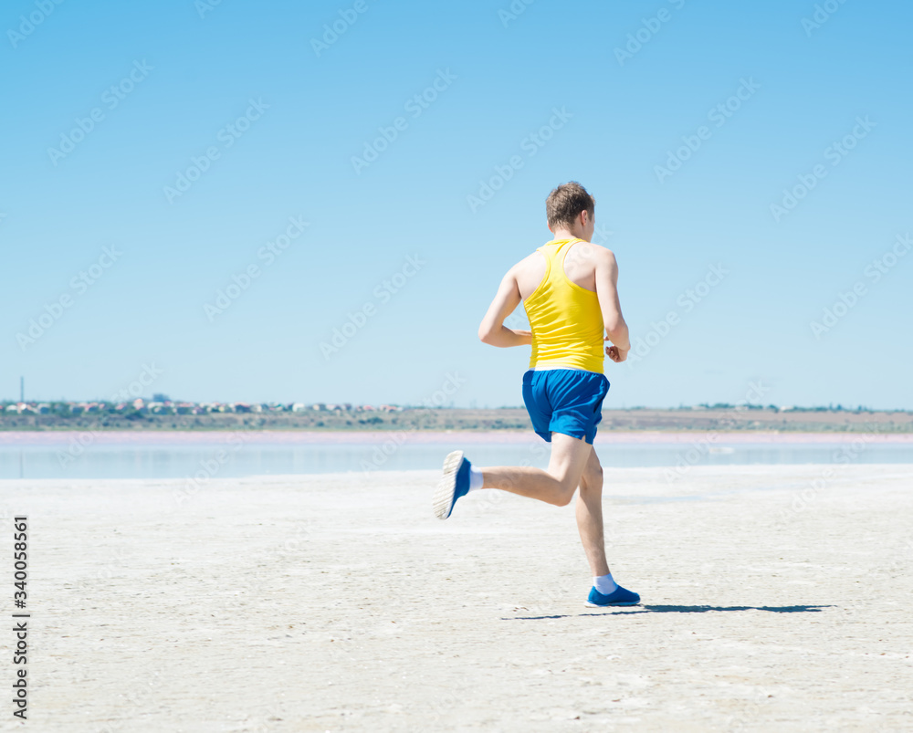 young man jogging on the beach in summer young man jogging on the beach in summer