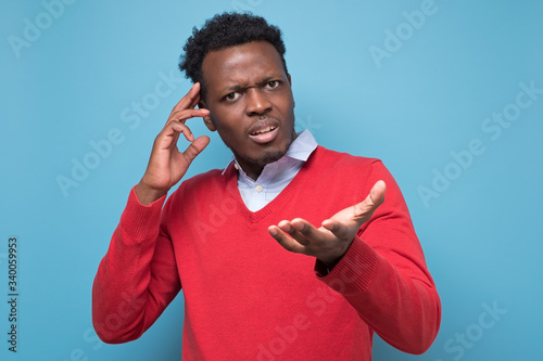 Pensive young african man against a blue background. What are you speaking about concept. Studio shot photo