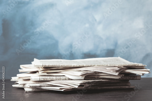 Pile of newspapers on blue background, space for design. Journalist's work photo