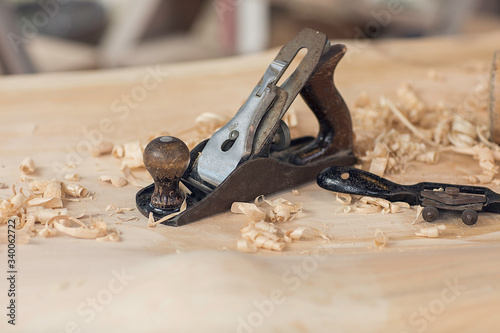 Wood shavings carpenter working with an old metal spokeshave and a blurry background. Light beige colored poplar wood with slight curves in it. Vintage woodworking, handwork, handmade