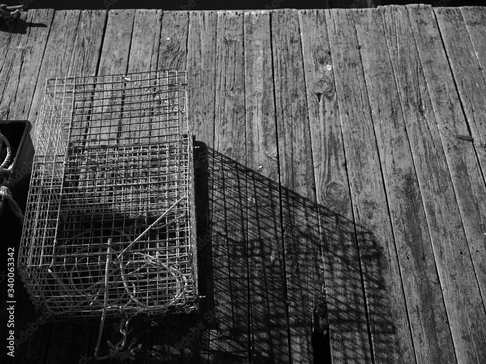Lobster trap casting long shadows on an old wooden dock