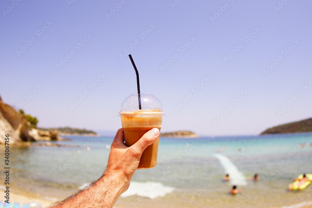 young man holding a cocktail in hand on the beach in vacation. young man holding a cocktail in hand on the beach in vacation.
