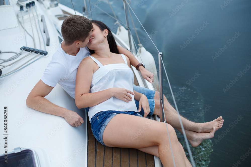 love story in nautical topics aboard the yacht. passionatehappy couple in love hugging and kissing on  sea water background.
Romantic date on seafront.
emotional man and woman have fun aboard the boat