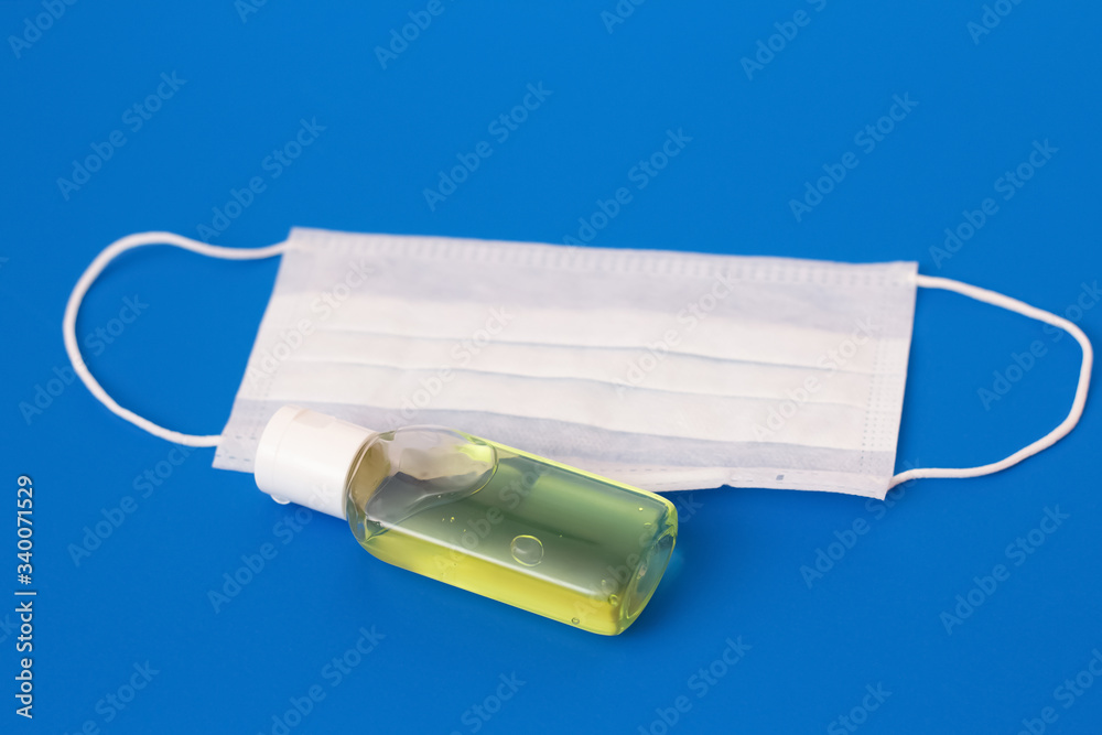 Hand antiseptic and white face mask on a blue background Hand antiseptic and white face mask on a blue background