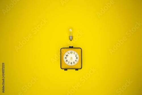 Yellow alarm clock and light bulb
 photo